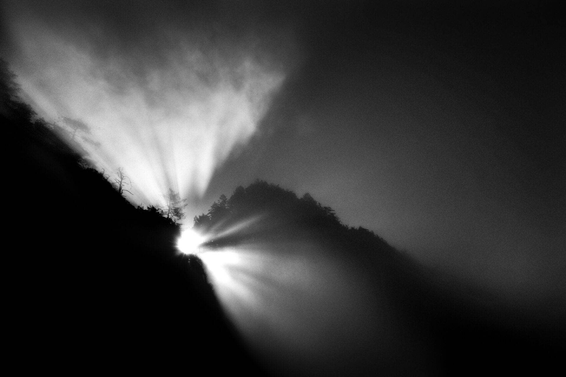 Top of mountain with sun poking through clouds