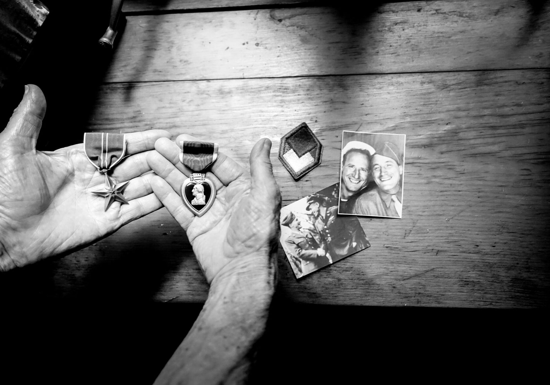 DSC00165-Edit (1) Black and white photo of a man's hands holding WWII medals.